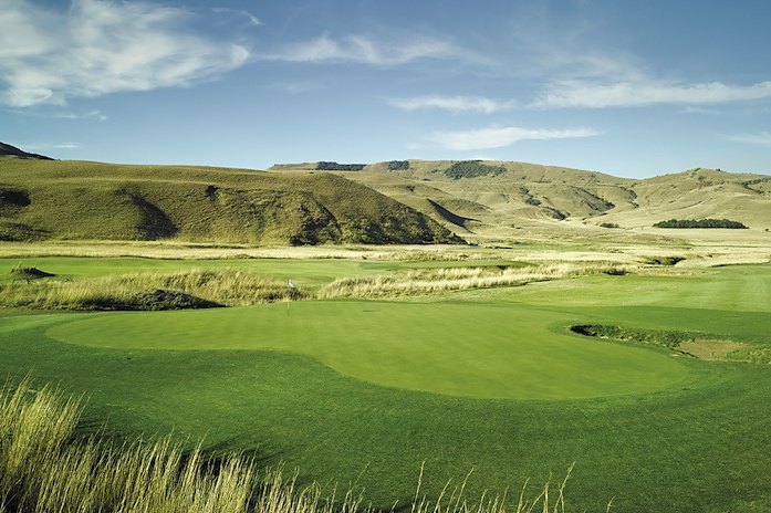 Golf course green framed by mountains